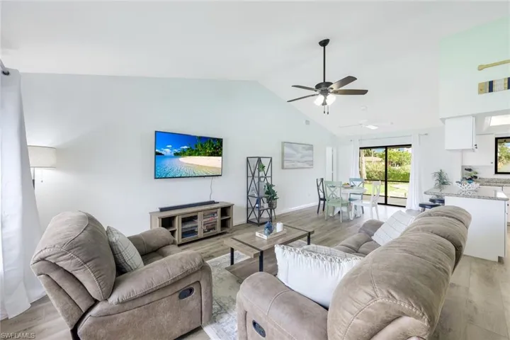 Living room with light hardwood / wood-style floors, high vaulted ceiling, and ceiling fan