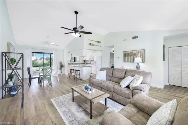 Living room featuring light hardwood / wood-style flooring, ceiling fan, and high vaulted ceiling