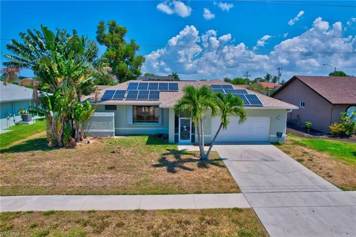 Ranch-style house featuring a garage, a front yard, and solar panels