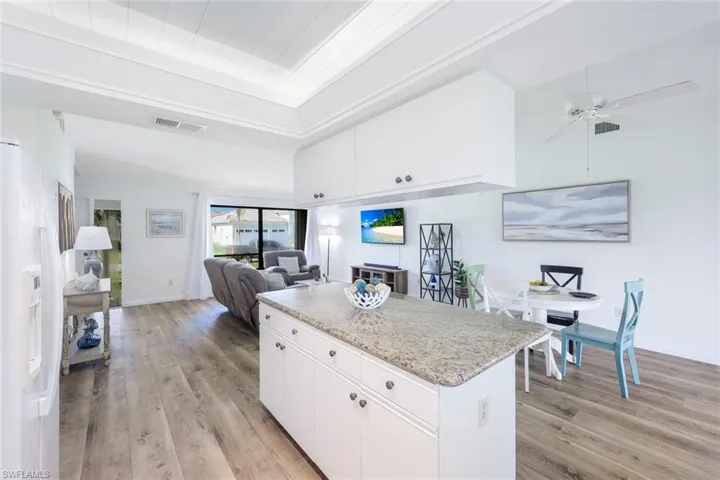 Kitchen with light hardwood / wood-style floors, white cabinetry, white refrigerator with ice dispenser, and ceiling fan