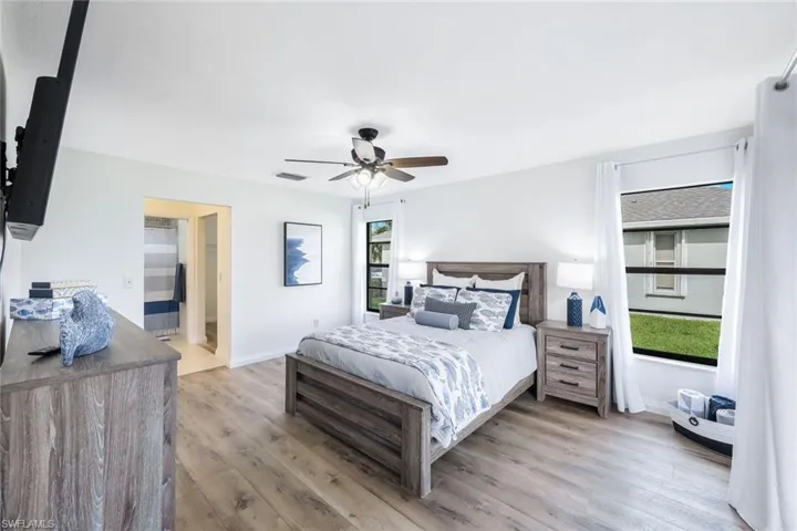 Bedroom featuring light hardwood / wood-style flooring, connected bathroom, and ceiling fan