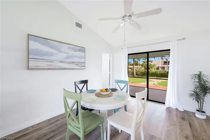 Dining room featuring hardwood / wood-style flooring, vaulted ceiling, and ceiling fan