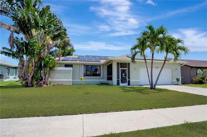 Single story home featuring a garage, a front yard, and solar panels