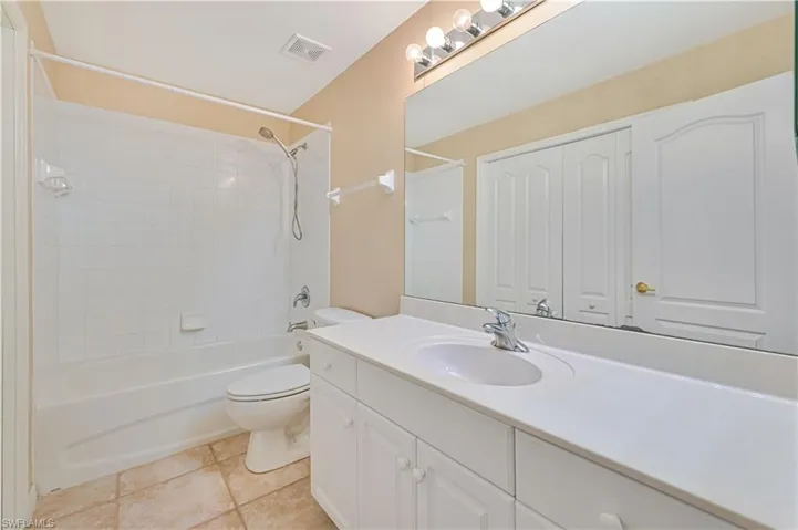 Full bathroom featuring tile floors, tiled shower / bath combo, vanity, and toilet