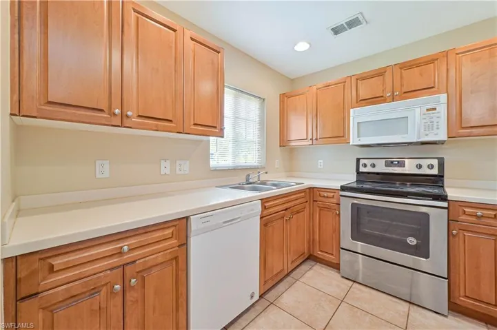 Kitchen featuring white appliances, sink, and light tile floors