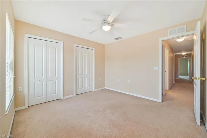 Unfurnished bedroom with multiple closets, ceiling fan, and light colored carpet