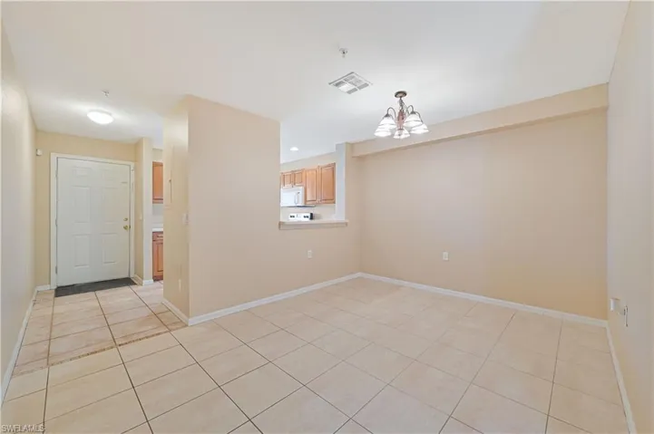Empty room with a notable chandelier and light tile flooring