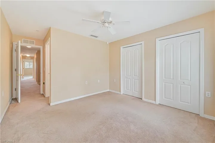 Unfurnished bedroom featuring two closets, ceiling fan, and light colored carpet