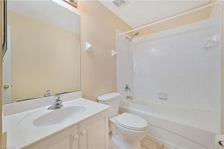 Full bathroom with tile floors, tiled shower / bath, toilet, and vanity