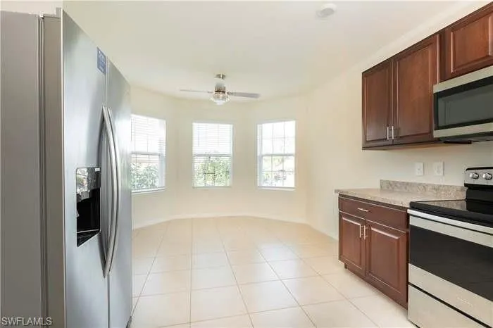 Kitchen with stainless steel appliances, light countertops, ceiling fan, and plenty of natural light