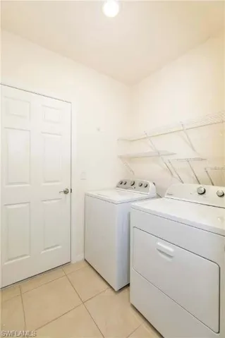Laundry room featuring light tile patterned floors and separate washer and dryer