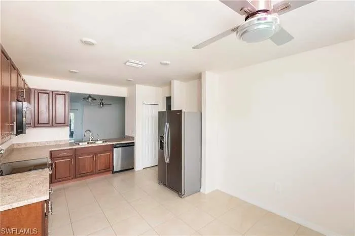 Kitchen with a ceiling fan, light countertops, stainless steel appliances, and wood finish cabinets