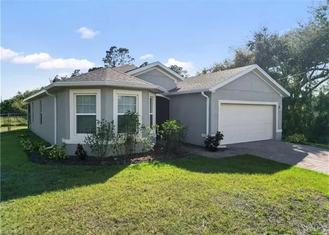 Ranch-style house with stucco siding, driveway, a front lawn, and a garage