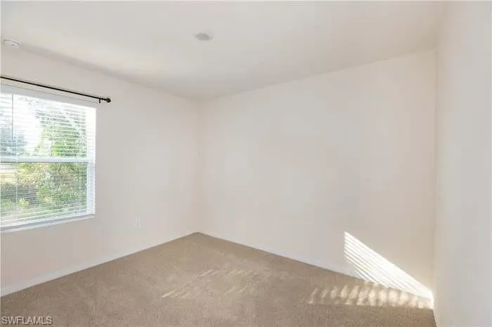Carpeted spare room featuring baseboards