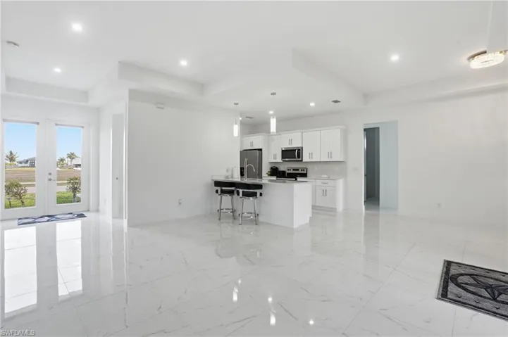 Kitchen featuring a kitchen bar, white cabinetry, open floor plan, and stainless steel appliances