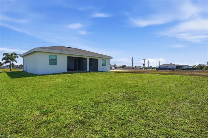 Back of property with stucco siding and a lawn
