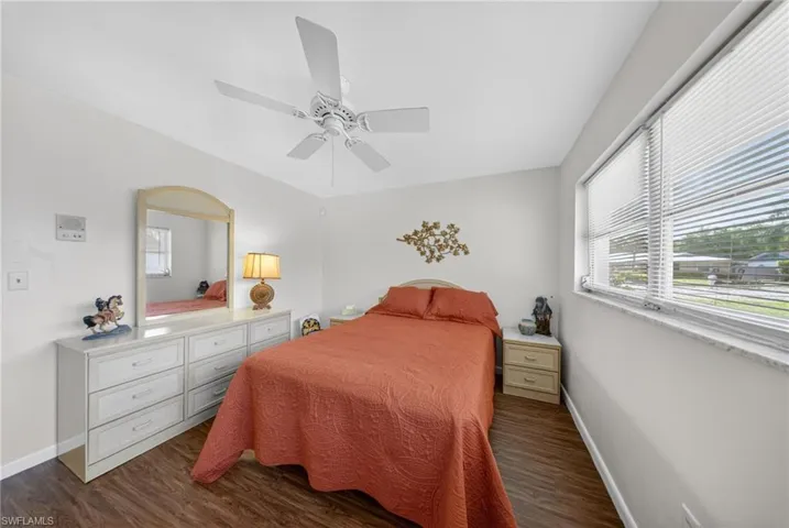 This room features wood-style flooring, a ceiling fan, and a window with horizontal blinds