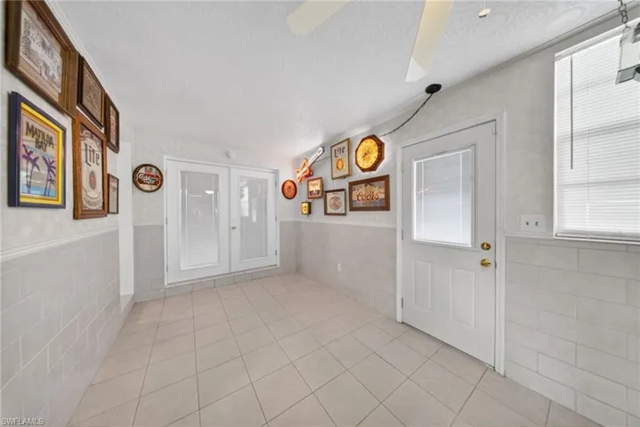 The property features white tiled flooring, a white ceiling fan, and white walls with a lower section of white tile