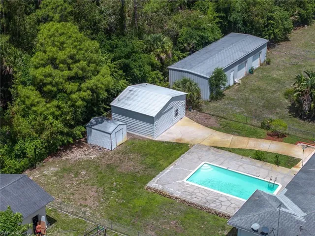 The property features a swimming pool with a surrounding concrete patio, a large metal outbuilding, a smaller detached garage, and a shed