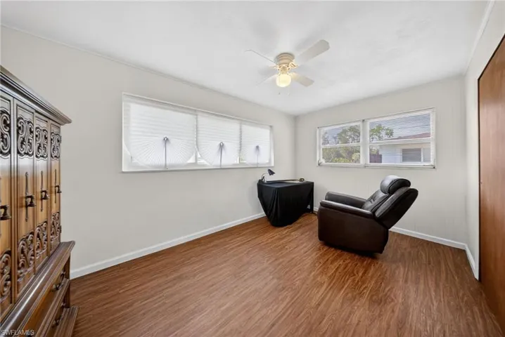 This room features wood-look flooring, white walls, and a ceiling fan