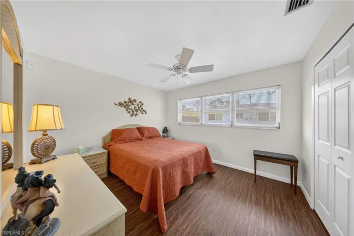 This room features dark wood-style flooring, light-colored walls, and a ceiling fan