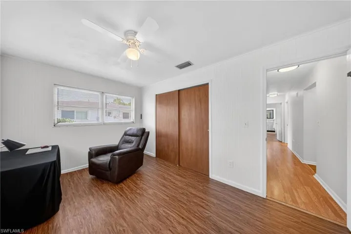 This room features wood-look flooring, white walls, and a ceiling fan with an integrated light fixture