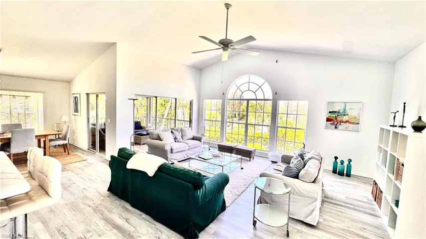 Living room with wood finished floors, plenty of natural light, high vaulted ceiling, and ceiling fan