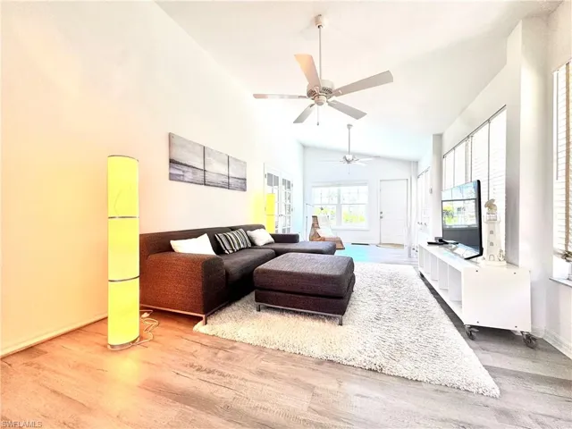 Living area featuring wood finished floors, a ceiling fan, and vaulted ceiling