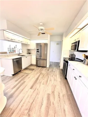 Kitchen featuring appliances with stainless steel finishes, light wood-style floors, light countertops, and a ceiling fan