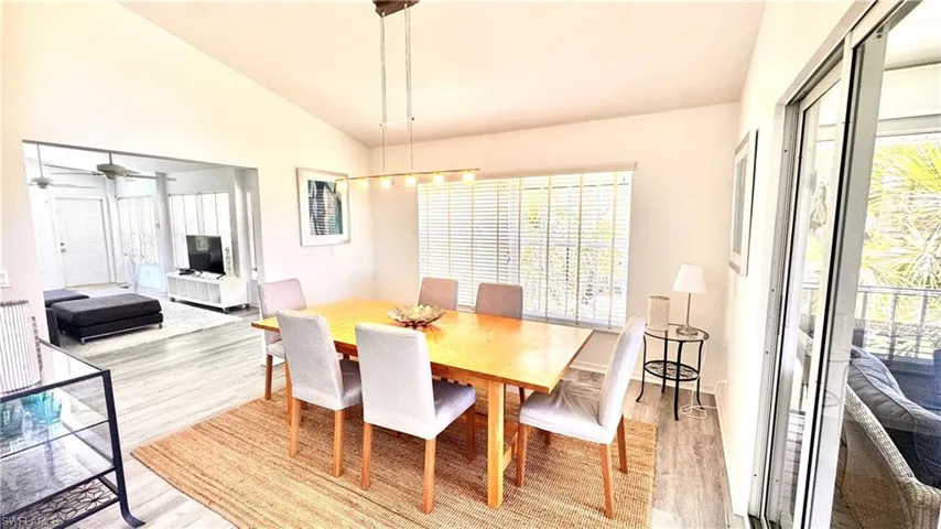 Dining area with light wood-style flooring, vaulted ceiling, healthy amount of natural light, and a ceiling fan