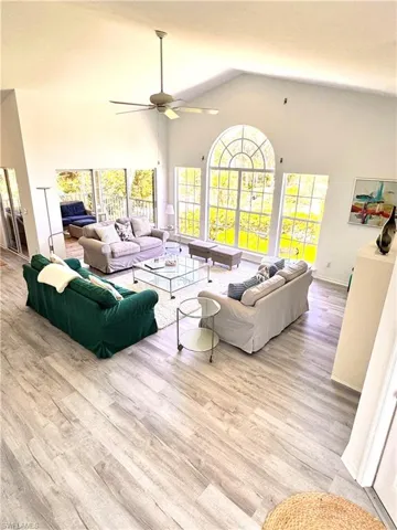 Living room featuring ceiling fan, wood finished floors, and high vaulted ceiling