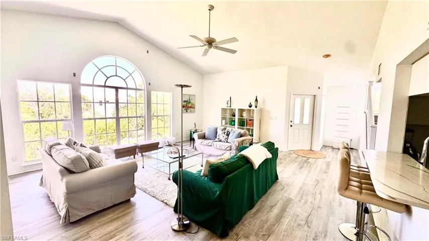 Living room with high vaulted ceiling, ceiling fan, and wood finished floors