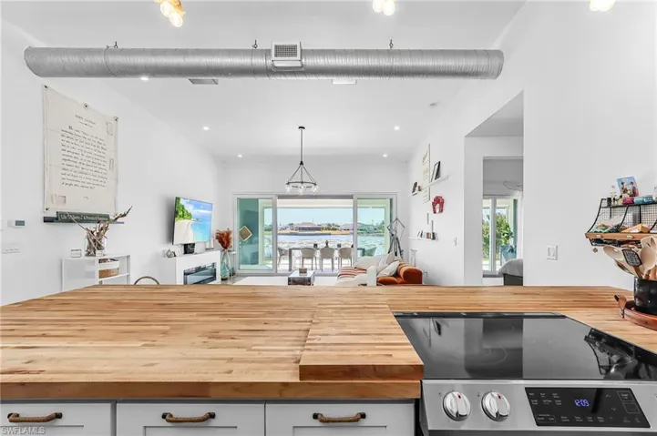 Kitchen with wood counters, stainless steel electric range oven, open floor plan, and hanging light fixtures