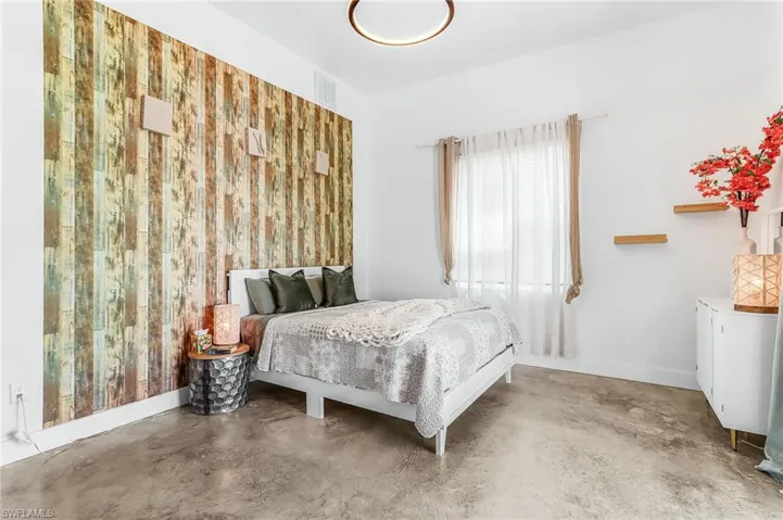 Bedroom featuring finished concrete floors and baseboards