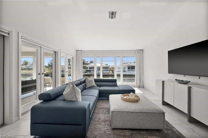 Primary bedroom sitting area featuring large windows and glass doors providing abundant natural light and views of the waterway