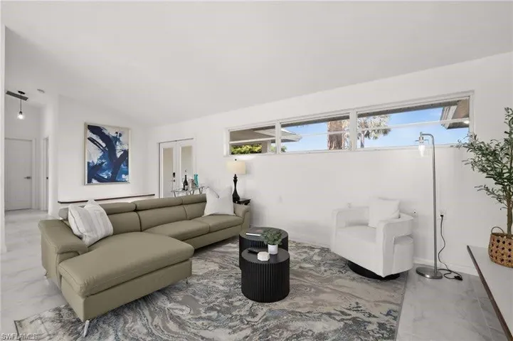 Living area featuring white walls, a large area rug, and a row of high windows