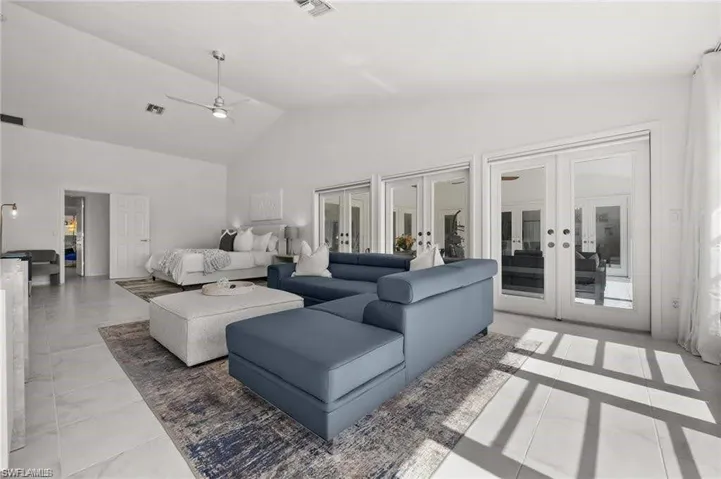 Spacious primary featuring white tile flooring, vaulted ceilings, and a ceiling fan