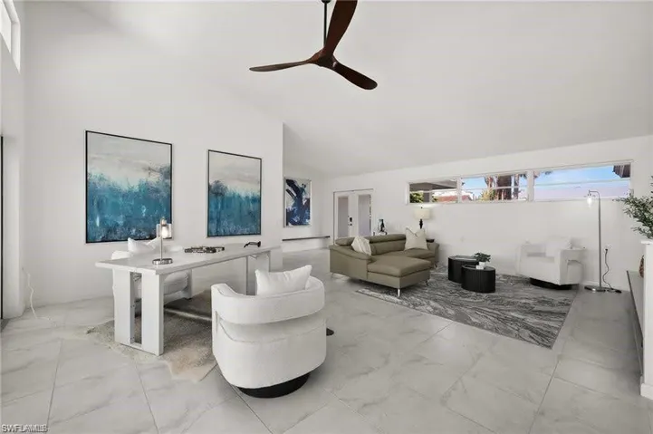 Expansive living area featuring vaulted ceilings, a ceiling fan, and large tile flooring