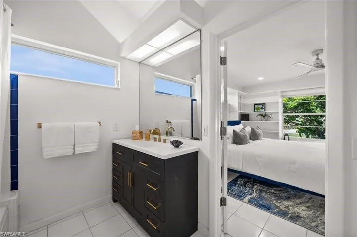 Bathroom featuring a dark vanity with gold hardware, white countertop, and a large mirror
