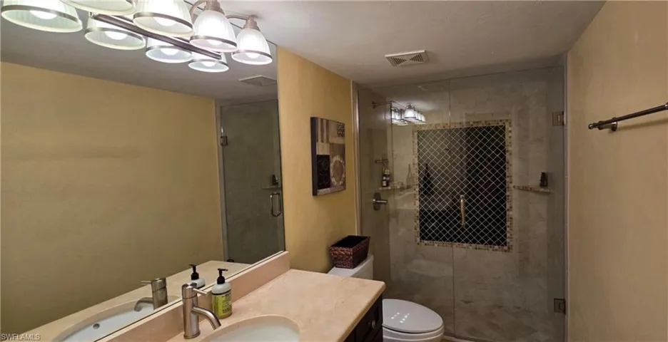 Bathroom featuring walk in shower, vanity, and toilet