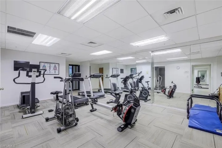 Workout area with a drop ceiling and light carpet