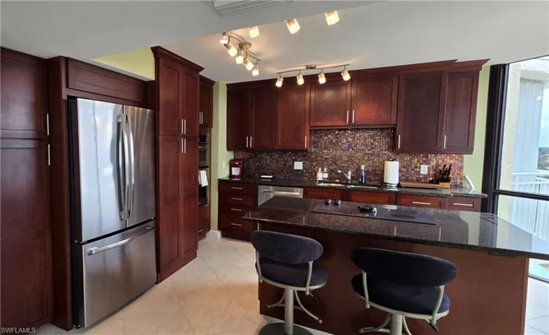 Kitchen featuring tasteful backsplash, a center island, stainless steel appliances, a breakfast bar, and dark stone countertops