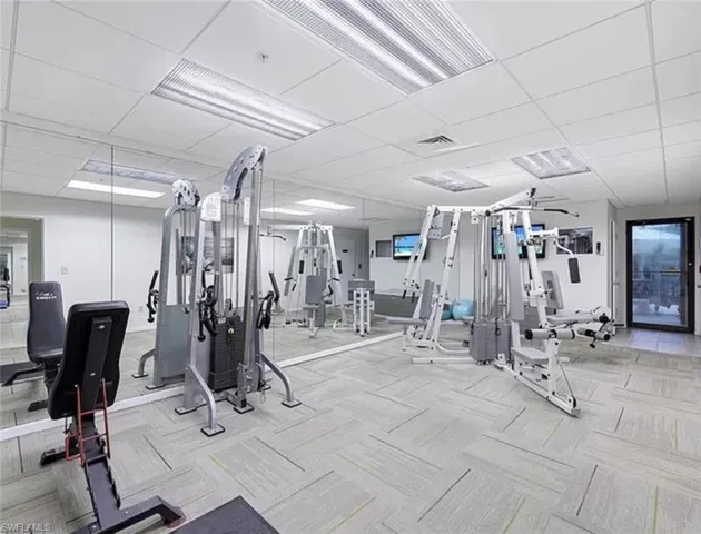 Workout area featuring a drop ceiling and light carpet