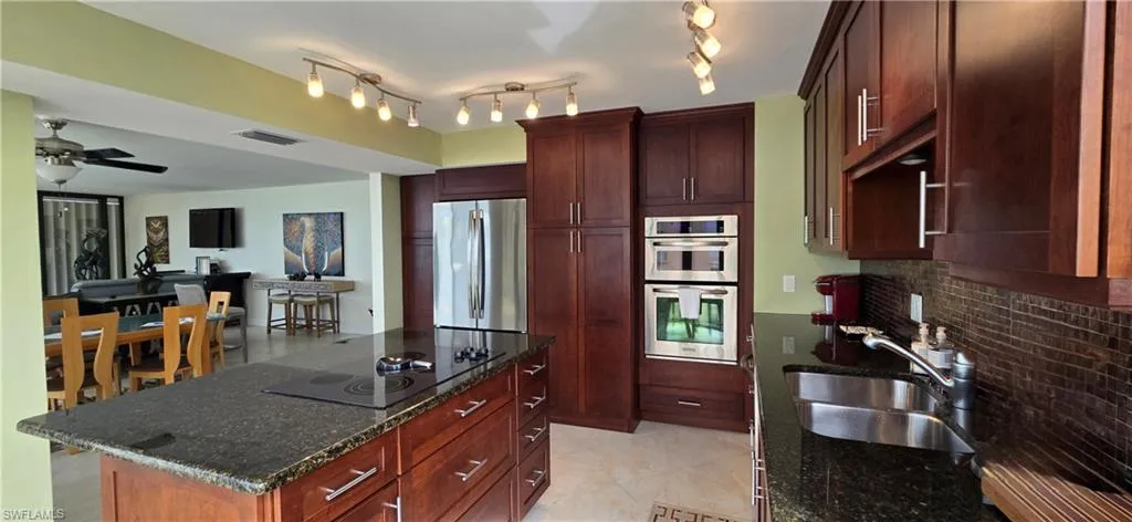 Kitchen with a kitchen island, stainless steel appliances, dark stone countertops, sink, and backsplash