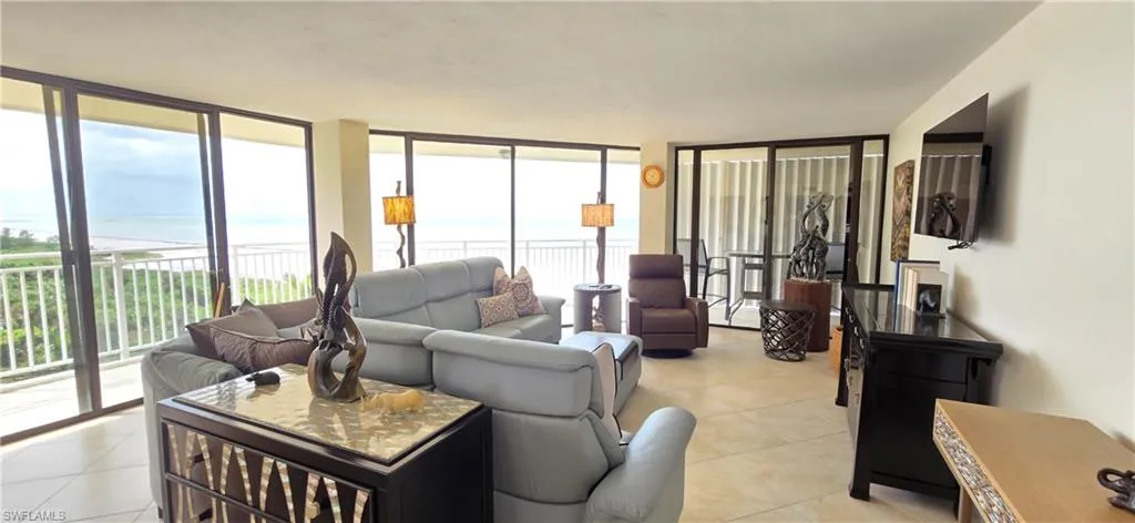 Tiled living room featuring floor to ceiling windows, a water view, and a wealth of natural light