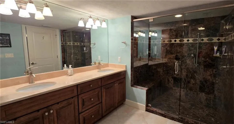 Bathroom with tile patterned flooring, an enclosed shower, and vanity