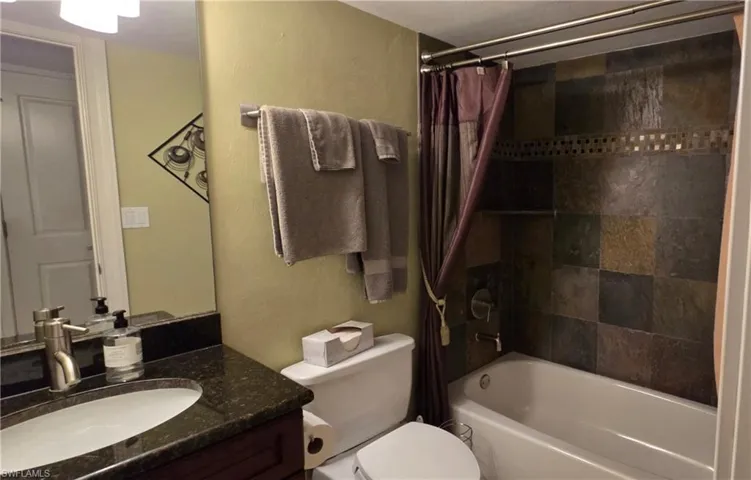 Full bathroom featuring vanity, toilet, and shower / bathtub combination with curtain