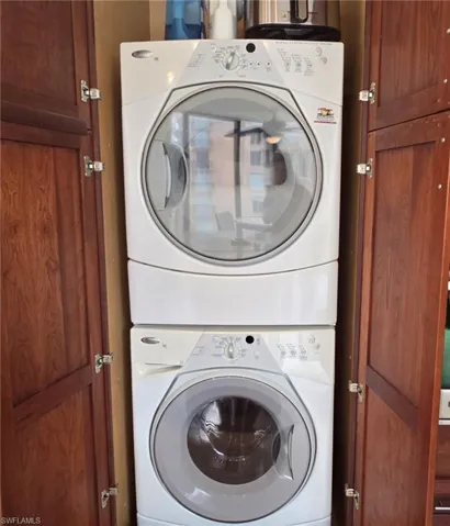 Laundry room featuring stacked washer and dryer and cabinets