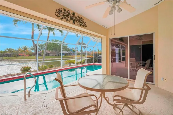 Sunroom / solarium with plenty of natural light, ceiling fan, a water view, and a swimming pool