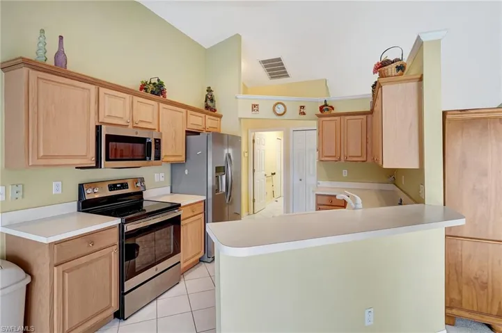 Kitchen featuring light countertops, visible vents, stainless steel appliances, light brown cabinets, and light tile patterned floors
